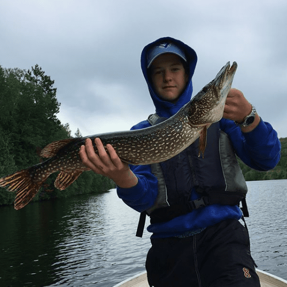 Boy holding up a large northern pike caught at black donald lake