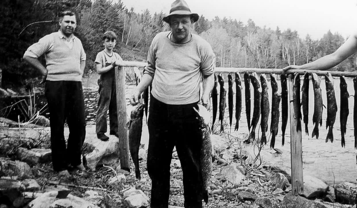 vintage photo of two men and a young boy with many northern pike caught that day
